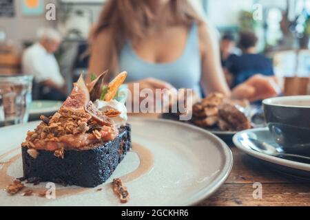 Sweet chocolate brownie with figs and whipped cream served on plate on table in cafe Stock Photo