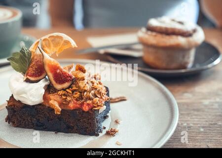 Sweet chocolate brownie with figs and whipped cream served on plate on table in cafe Stock Photo