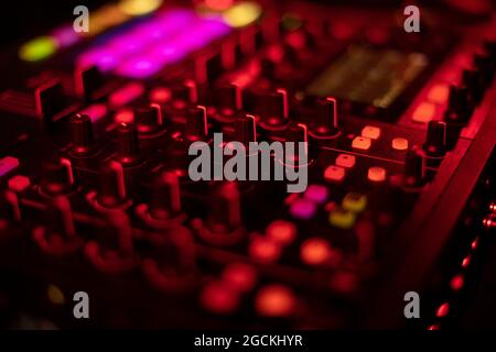 Music mixer in the dark. The buttons on the remote are lit. Sound player neon glow. DJ console for playing music. Stock Photo