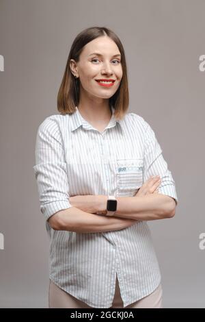 Portrait of happy woman standing folded hands wearing shirt and smartwatch isolated on pink background Stock Photo