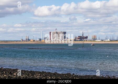 Hartlepool Nuclear Power Station and decommisioned oil rigs at Seaton Port as viewed from South Gare,Redcar,England,UK Stock Photo