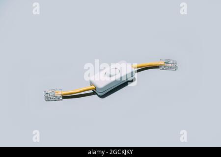 Conceptual shot of network cable with switch button isolated on grey background Stock Photo