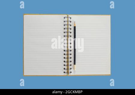 Opened notebook with a pencil on it with a blue background Stock Photo