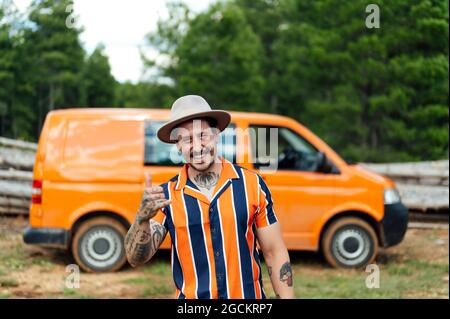 Serious male traveler leaning on van parked in nature and looking at camera during summer adventure Stock Photo