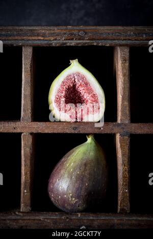 Ripe halved and whole figs placed on shabby wooden shelf on rustic kitchen Stock Photo