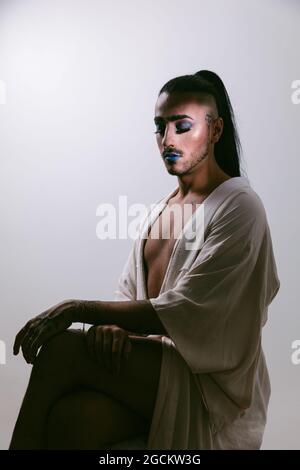 Portrait of glamorous transgender bearded Woman in sophisticated make with closed eyes against neutral background Stock Photo