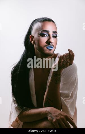 Portrait of glamorous transgender bearded Woman in sophisticated make looking at camera against neutral background Stock Photo