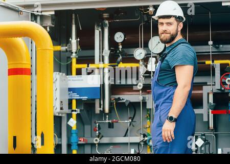 Caucasian worker at gas distribution station opens valve on gas supply ...