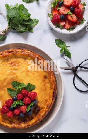 From above view of cheesecake decorated with raspberries, blueberries and mint leaves, placed on marble table Stock Photo