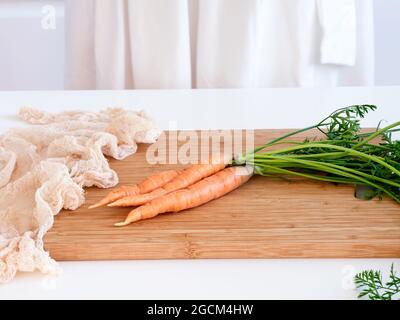 Three orange carrots lying on a cutting board. Close up. Stock Photo