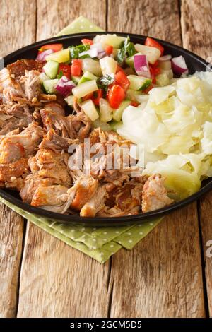 Hawaiian Style Slow Cooker Kalua Pork served with stewed cabbage and fresh salad closeup in the slate plate on the table. Vertical Stock Photo