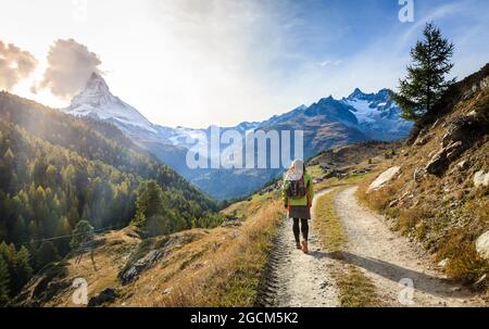 Young woman walking along a trail in the mountains near Swiss resort town of Zermatt Stock Photo