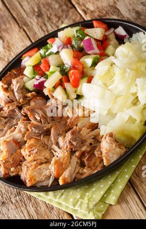 Kalua Pork the famous luau style pork made easy in the slow cooked served with stewed cabbage and fresh salad closeup in the slate plate on the table. Stock Photo