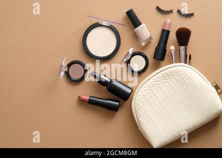 Makeup bag with fashion makeup cosmetic accessories on brown background. Flat lay, top view. Stock Photo