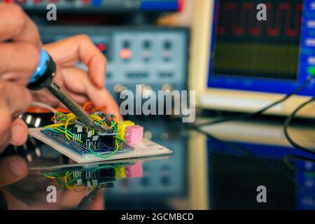Manufacturing and setting up an electronic device in the laboratory. Soldering iron and electronic measuring instruments Stock Photo