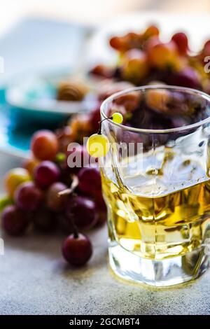 Glass of Georgian chacha brandy next to a bunch of red grapes on a table Stock Photo