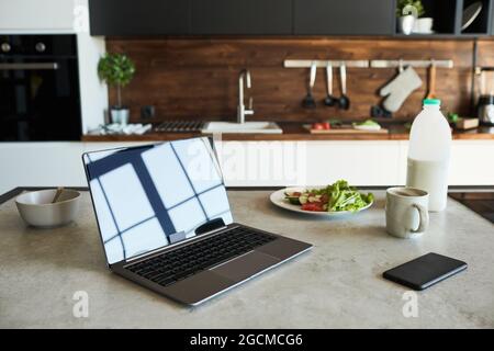 Background image of opened laptop with blank screen on kitchen counter in graphic loft design, copy space Stock Photo