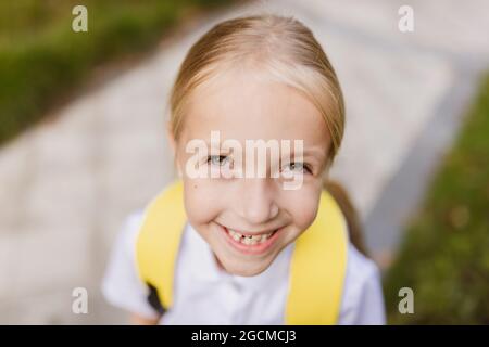 Schoolgirl back to school after summer vacations. Pupil in uniform smiling early morning outdoor.  Stock Photo