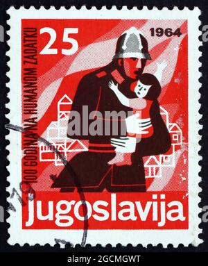 YUGOSLAVIA - CIRCA 1964: a stamp printed in Yugoslavia shows Fireman Rescuing Child, Centenary of Voluntary Fireman, circa 1964 Stock Photo