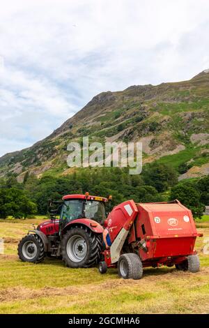 Red tractor towing baling machine, hay baler, straw baler, agriculture, agricultural machinery, agricultural implements, seasonal harvest, red tractor Stock Photo