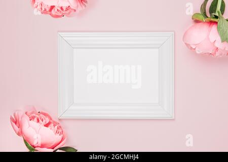 Mockup photo frame on a pink background with flowers. Delicate elegant background with pink peonies, peony buds. Flat lay, top view Stock Photo