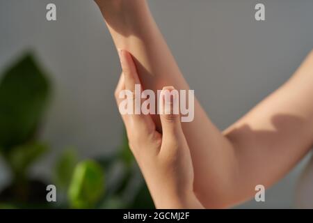 Smiling young woman applies cream on her hands Stock Photo