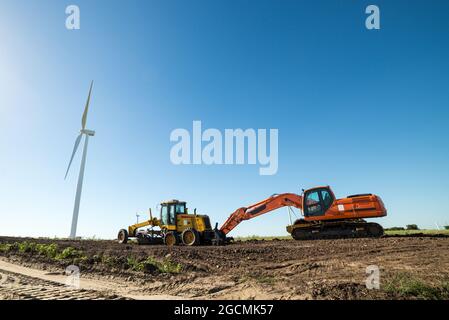 A wind turbines and other heavy machinery used for the assembly of more turbines, in a wind energy farm Stock Photo