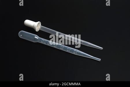 Macro closeup of glass dropper and plastic with white rubber top isolated on black background Stock Photo