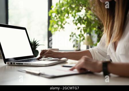 Beautiful Female Data Analyst sitting at the Table Works on a Laptop. Stylish Woman in the Modern Office Environment. Stock Photo