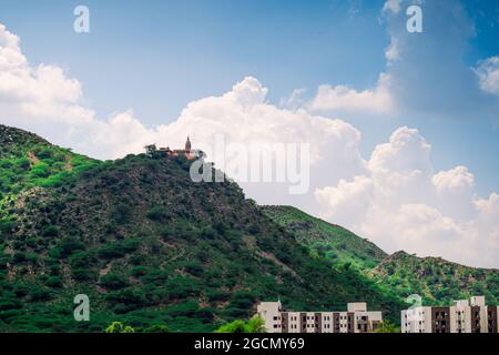 clouds moving behind a small hindu hill side temple mansa chandi devi on aravali hills in rajasthan a popular travel destination during the monsoon Stock Photo