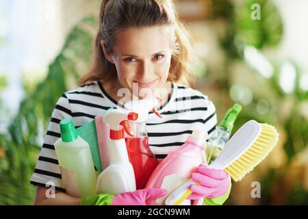 https://l450v.alamy.com/450v/2gcn9wm/portrait-of-happy-modern-middle-aged-housewife-in-striped-shirt-with-cleaning-supplies-in-the-modern-living-room-in-sunny-day-2gcn9wm.jpg