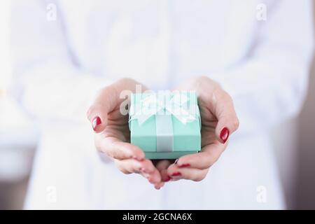 Small turquoise gift box in female hands closeup Stock Photo