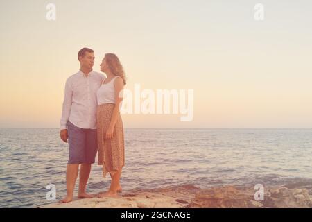 Young adult couple against sea in the rays of setting sun Stock Photo