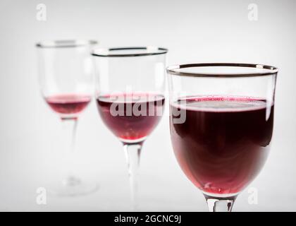 Three wine glasses in a row where their wine levels are level.  Focus on front glass while remaining glasses blur into the background. Stock Photo