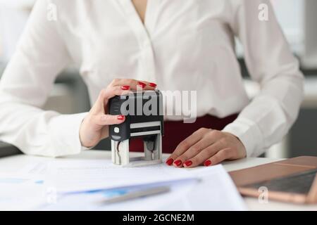 Businesswoman puts stamp on credit documents at work desk. Small and medium business development concept Stock Photo