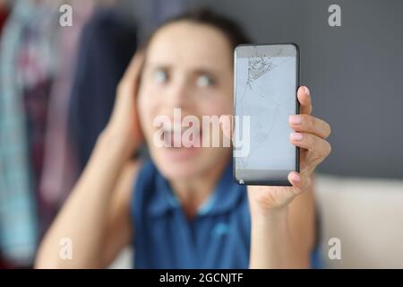 Upset woman holding broken smartphone in hands Stock Photo
