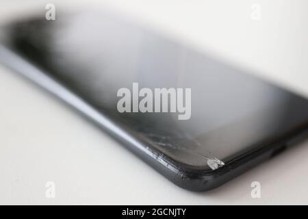 Smartphone with broken front screen is lying on table closeup Stock Photo