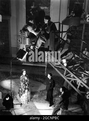 MERLE OBERON Director HAROLD YOUNG and Cinematographer HAROLD ROSSON on set candid with Camera Crew on Crane during filming of THE SCARLET PIMPERNEL 1934 director HAROLD YOUNG book Baroness Orczy Miss Oberon's dresses Oliver Messel producer Alexander Korda London Film Productions / United Artists Stock Photo