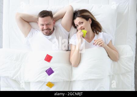Happy man woman lie on bed with condoms Stock Photo