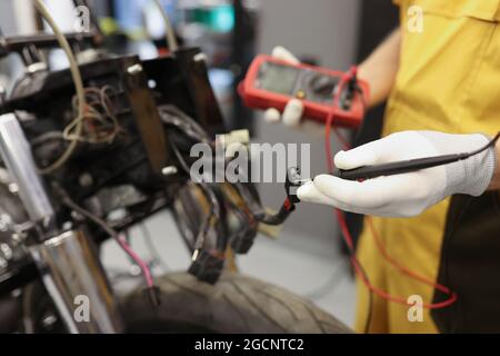Electronics repair service master using multimeter tester to determine the problem part Stock Photo