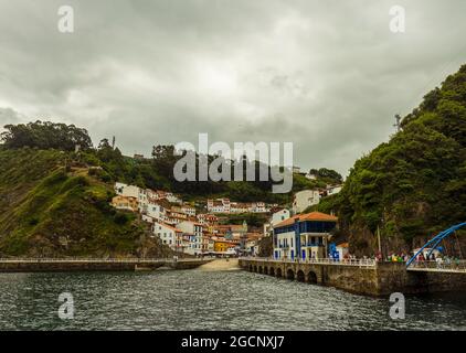 Cudillero, Asturias, Spain: Scenic view of colorful houses situated on a cliff which overlooks the small fishing port captured in the rainy day. Stock Photo