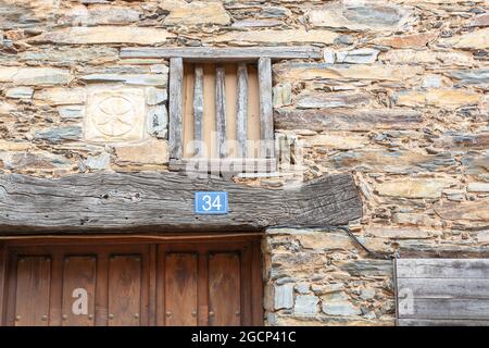 ROBLEDILLO DE GATA, SPAIN - Mar 27, 2021: wooden window without glass on the mezzanine floor of an old house made of slate and adobe next to an old sy Stock Photo