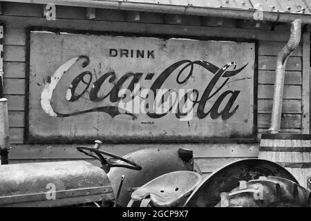 A vinatge tractor parked under a rusted sign for Coca Cola at the Mast General Store in Valle Crucis, North Carolina. Stock Photo