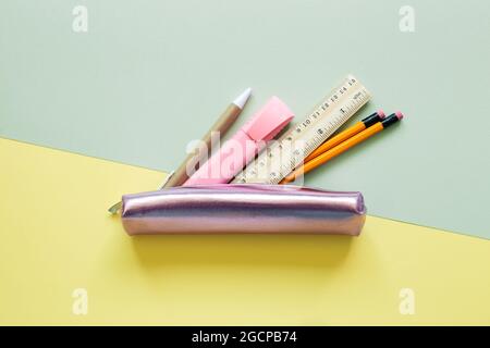 Pencil case with stationery on green and yellow background. top view, copy space Stock Photo