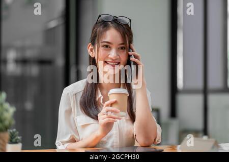 Portrait of young asian businesswoman beautiful charming smiling and talking on the mobile phone in the office Stock Photo