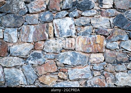 Texture of the masonry. Background of the surface of colored stones of uneven shape. Top view. Stock Photo