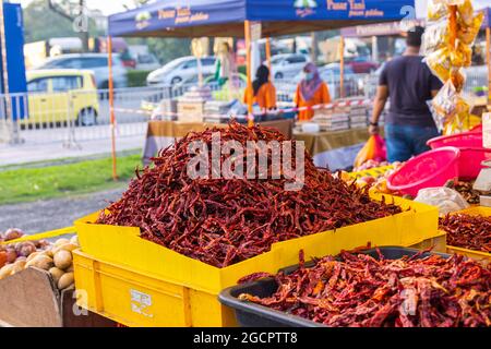 A bunch of dried red chili peppers or chilli pods on the counter of vegetable seller stand in a fresh market at Kuala Lumpur. Chilli is the most used