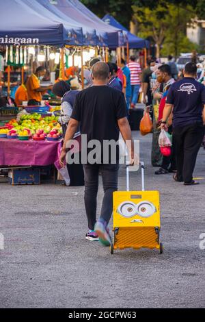 The fresh market in Putrajaya, near the capital Kuala Lumpur, is busy. Man carries his purchases in a Minion handcart or trolley. Stock Photo