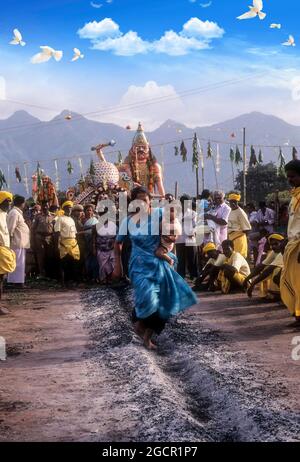 A woman carrying a child on her hip and running on burning coal; Fire walking festival at Vana Badra Kali Amman Temple at Nellithurai near Stock Photo