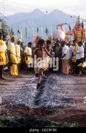 A boy running on burning coal; Fire walking festival at Vana Badra Kali Amman Temple at Nellithurai near Mettupalayam, Tamil Nadu, India Stock Photo